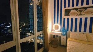 A bedroom with a city view, a vanity with a mirror, and striped walls. - Twin Galaxy (Johor Bahru)