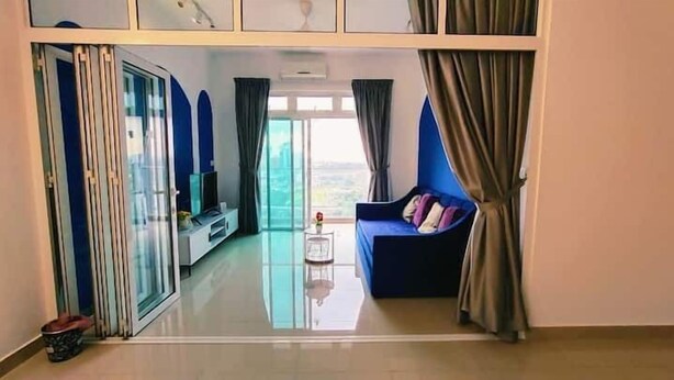 A modern living room with a glass partition, a blue sofa, and a television. - Twin Galaxy (Johor Bahru)