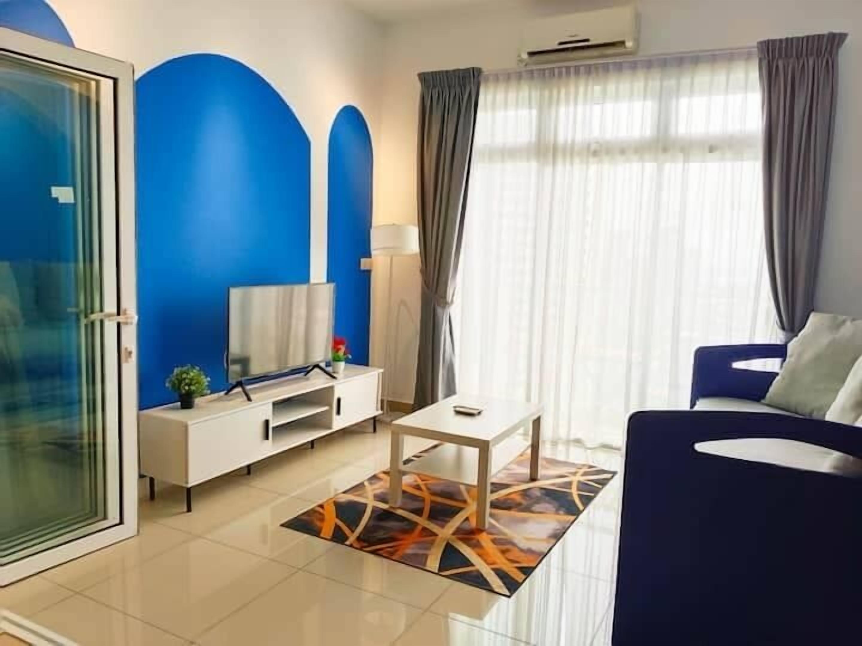 Uma sala de estar moderna com uma parede azul de destaque, uma televisão de tela plana, uma mesa de console branca, uma mesa de centro e um sofá azul.