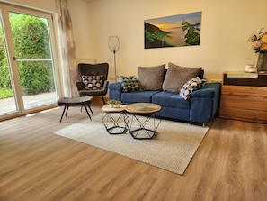 A living room with a sofa, armchair, coffee table, and a painting on the wall. - Holiday Apartment '5 Traminer' with Mountain View, Shared Terrace and Wi-Fi (Iphofen)