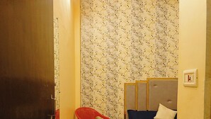A small, compact room with a bed, a red chair, and a door marked with the number 105.