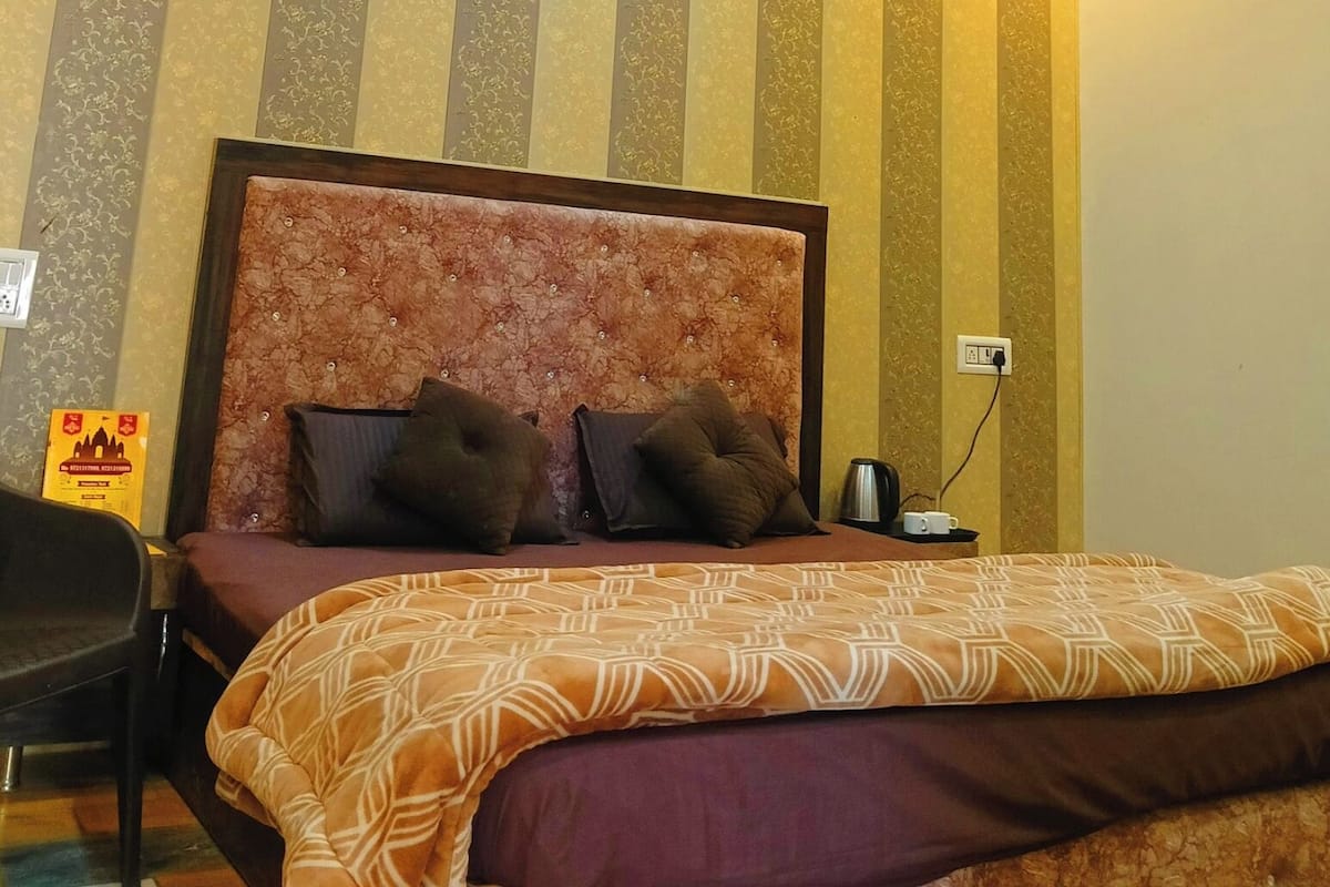 Una habitación de hotel con una cama, cabecera y ventilador de techo.