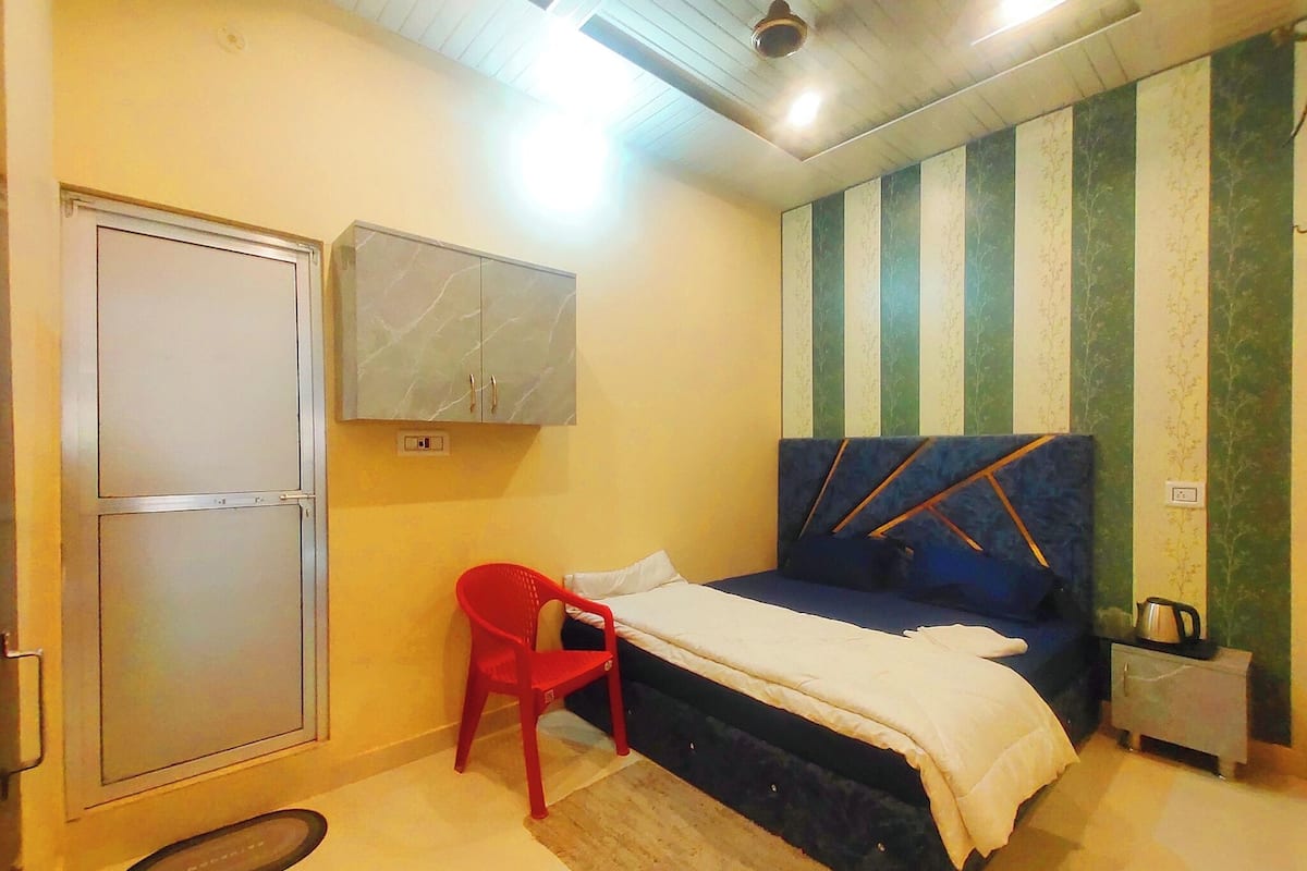 Un dormitorio con una cama, una silla roja, un armario y una mesita de noche.