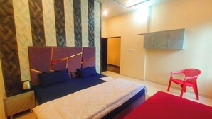 A bedroom with a bed, a red chair, a wardrobe, and a TV on the wall.