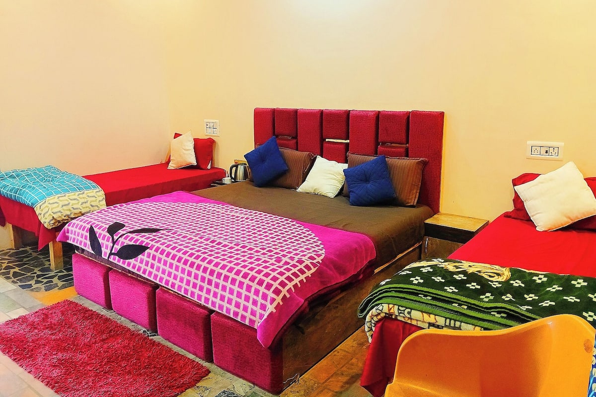 Una habitación con una cama grande, dos camas más pequeñas y un cabecero rojo.