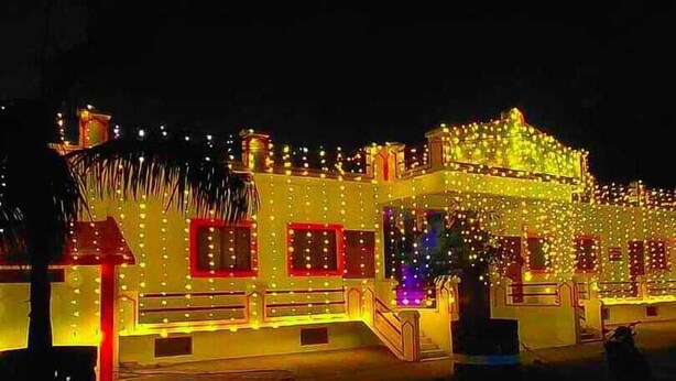 A building with multiple windows and a central entrance, surrounded by decorative lights.