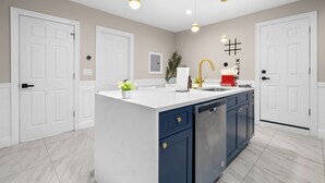 Una cocina moderna con armarios blancos, una isla central y un lavavajillas de acero inoxidable.