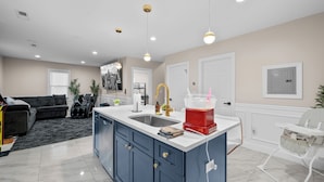 Una cocina moderna con una isla central, pileta doble e iluminación colgante.