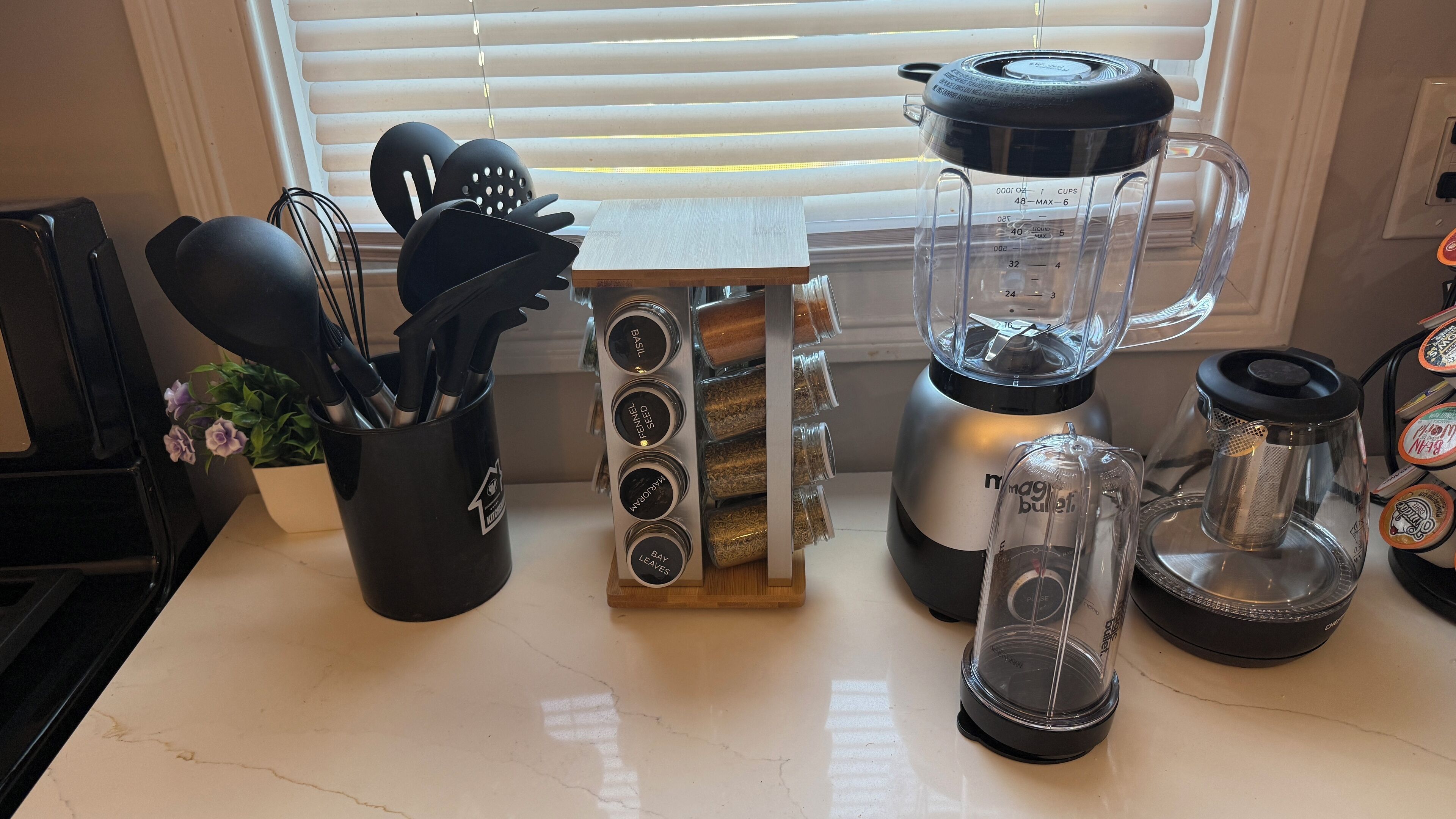 Una encimera de cocina con una licuadora, un especiero y una cafetera.