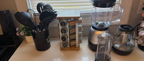 Una encimera de cocina con una licuadora, un especiero y una cafetera.