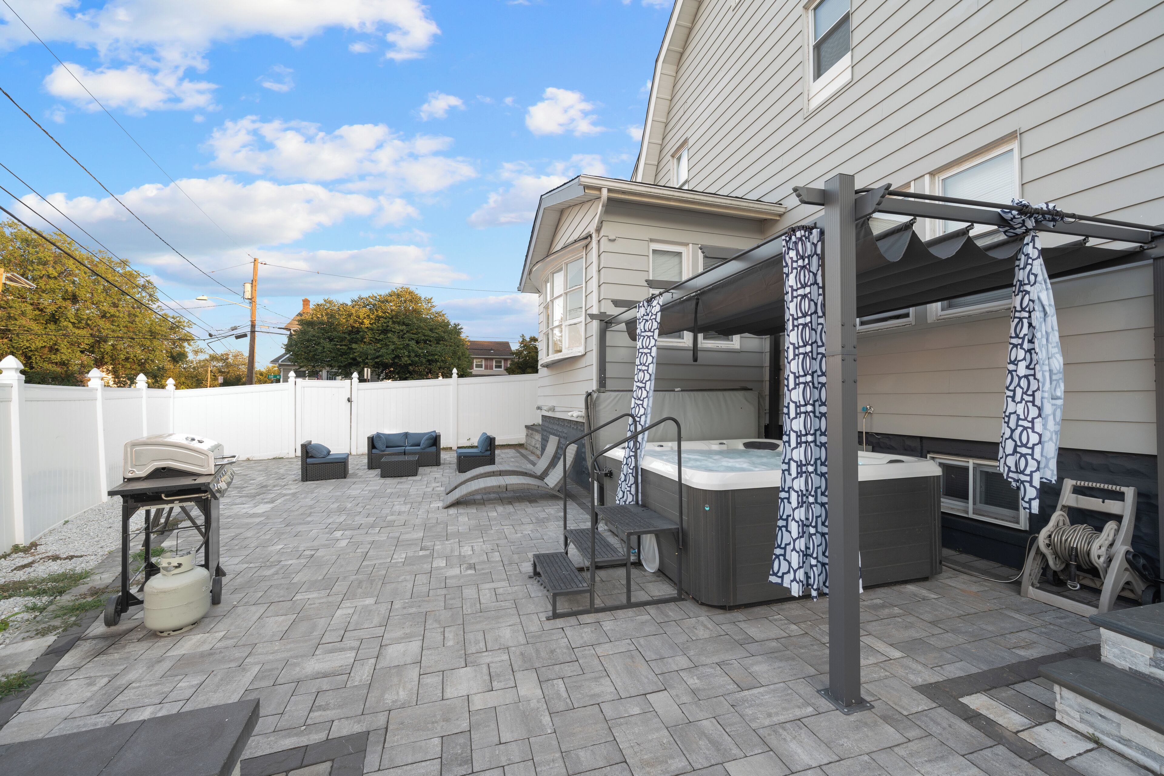Eine Terrasse mit Gartenmöbeln, einem Whirlpool und einem Grill.