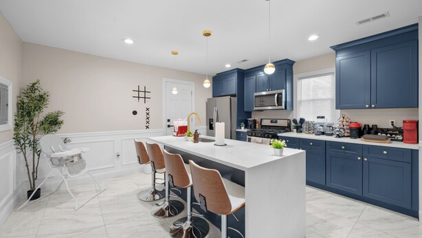 Una cocina moderna con una isla central, taburetes de bar y armarios azules.