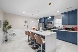 Une cuisine moderne dotée d’un îlot central, de tabourets de bar et de meubles de couleur bleue.