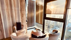 A modern living room with a large window, wooden flooring, and a city view. - Best Pool With 360 View of Pattaya & Best Location (Pattaya)