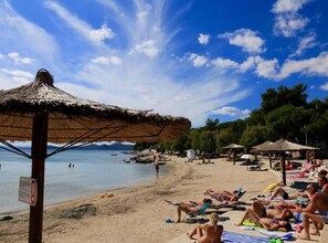 A beach with people sunbathing, umbrellas, and a thatched roof structure. - TJ Escape - Mobile Home With Hot Tub And Terrace (Pakostane)