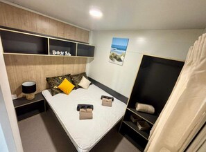 A modern bedroom with a bed, bedside tables, a headboard, and a view of the sea. - TJ Escape - Mobile Home With Hot Tub And Terrace (Pakostane)