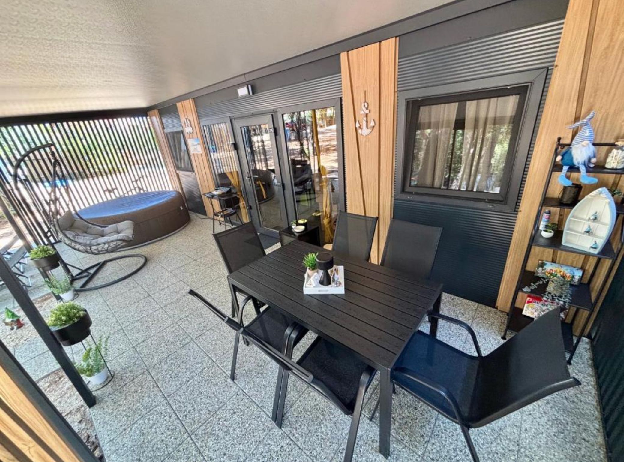 Eine moderne Außenpatio mit Esstisch, Stühlen und einer gepolsterten Sitzecke.