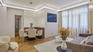 A modern living room with a dining area, a sofa, a coffee table, and a vase with dried flowers. - Superb AC Apartment Roosevelt Saint Honore (Paris)