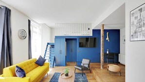 En moderne stue med en gul sofa, et træbord og en blå lænestol.