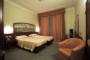 Une chambre d’hôtel avec deux lits, un grand miroir, une chaise et un tableau au mur.
