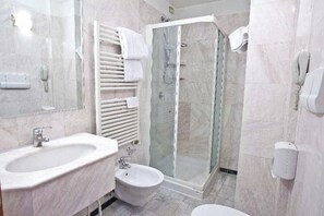 A bathroom with a marble sink, a bidet, a glass shower enclosure, and a towel rack. - Mythos (Milan)