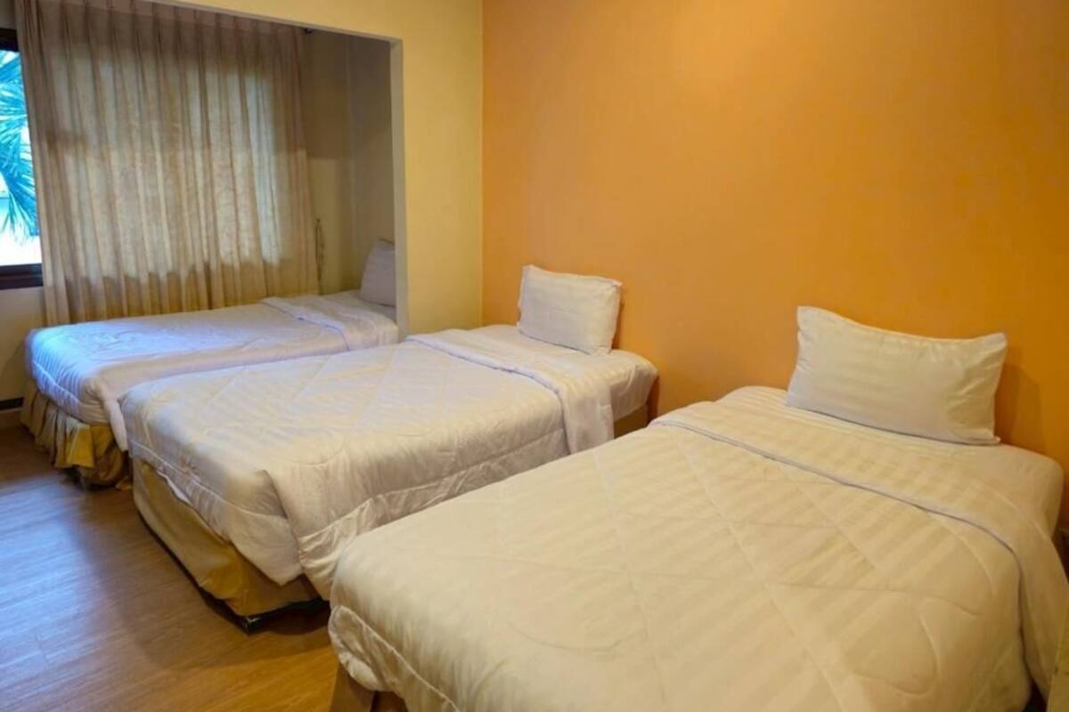 A hotel room with two beds, a window with curtains, and a wooden floor.