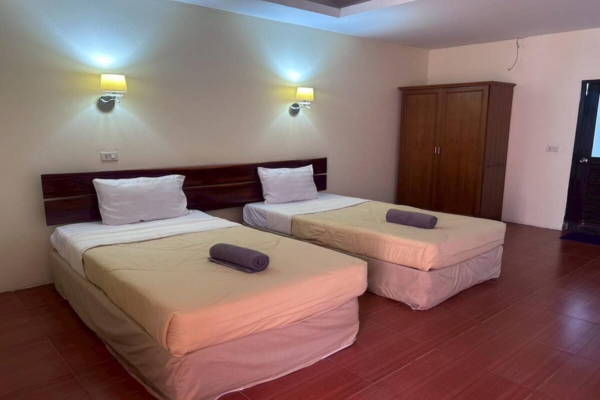 A room with two beds, a wardrobe, and wall-mounted lights.