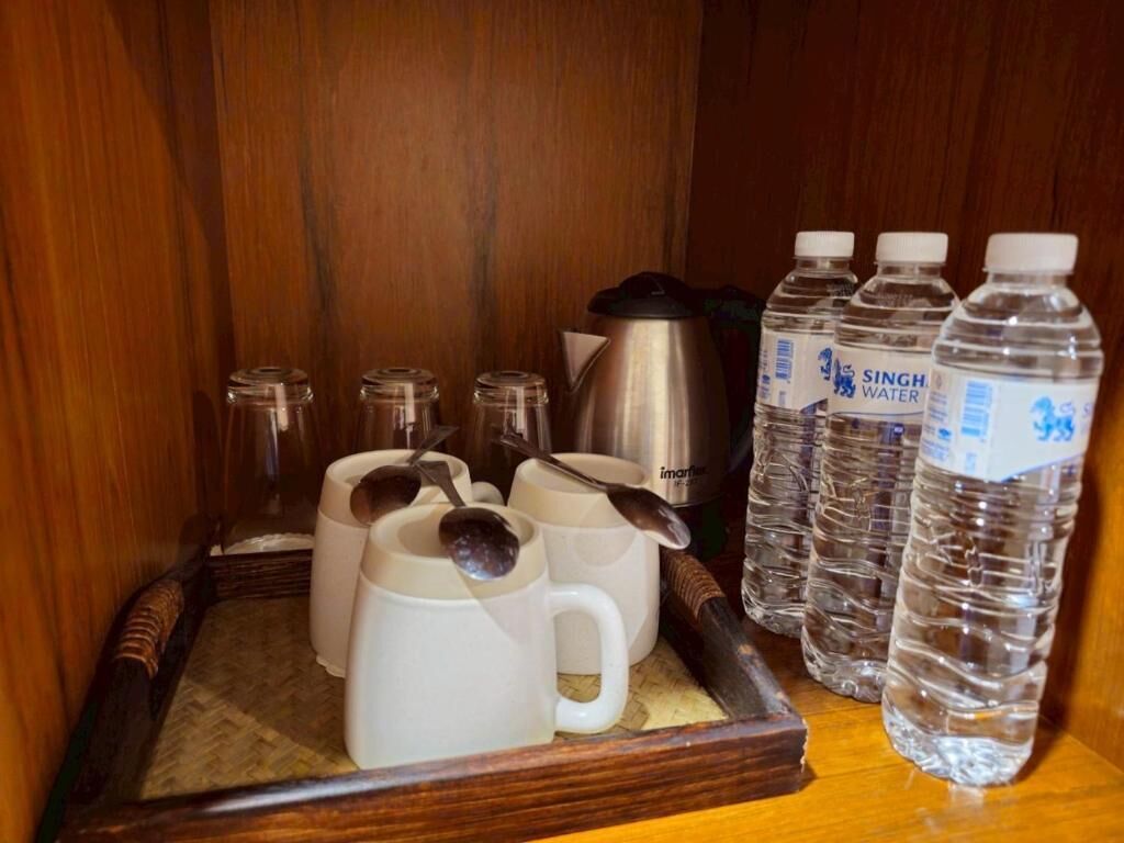 A tray with mugs, a kettle, and water bottles on a wooden surface.