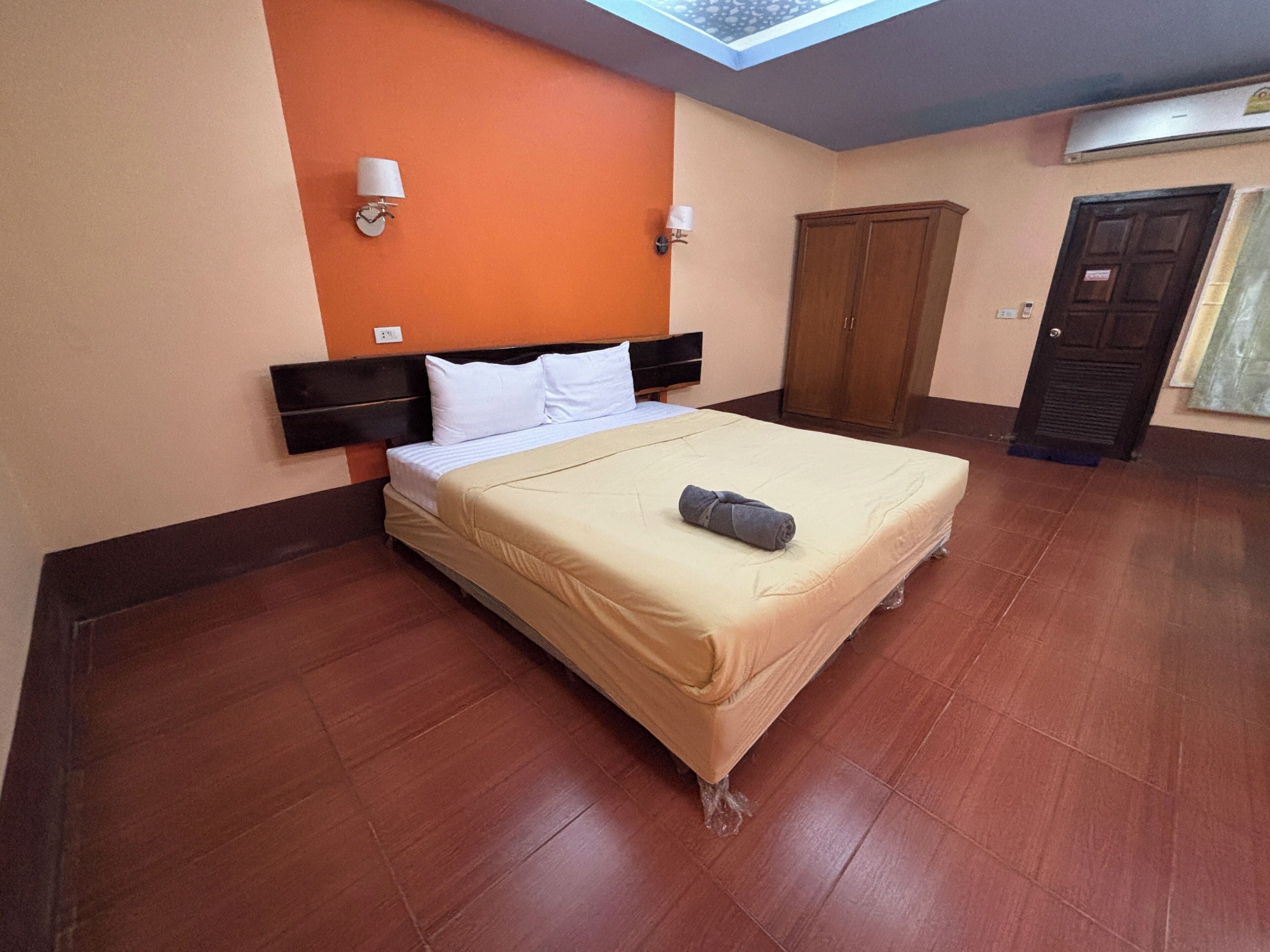 A hotel room with a bed, a wardrobe, and a door.