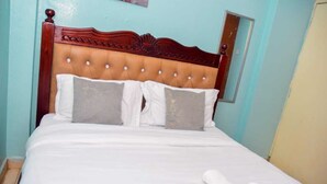 A neatly made bed with a wooden headboard, two pillows, and a rolled-up towel on a white bedspread. - Cozy 1-bedroom bed & breakfast in Nairobi, Mirema drive.
Home Away From Home (Nairobi)