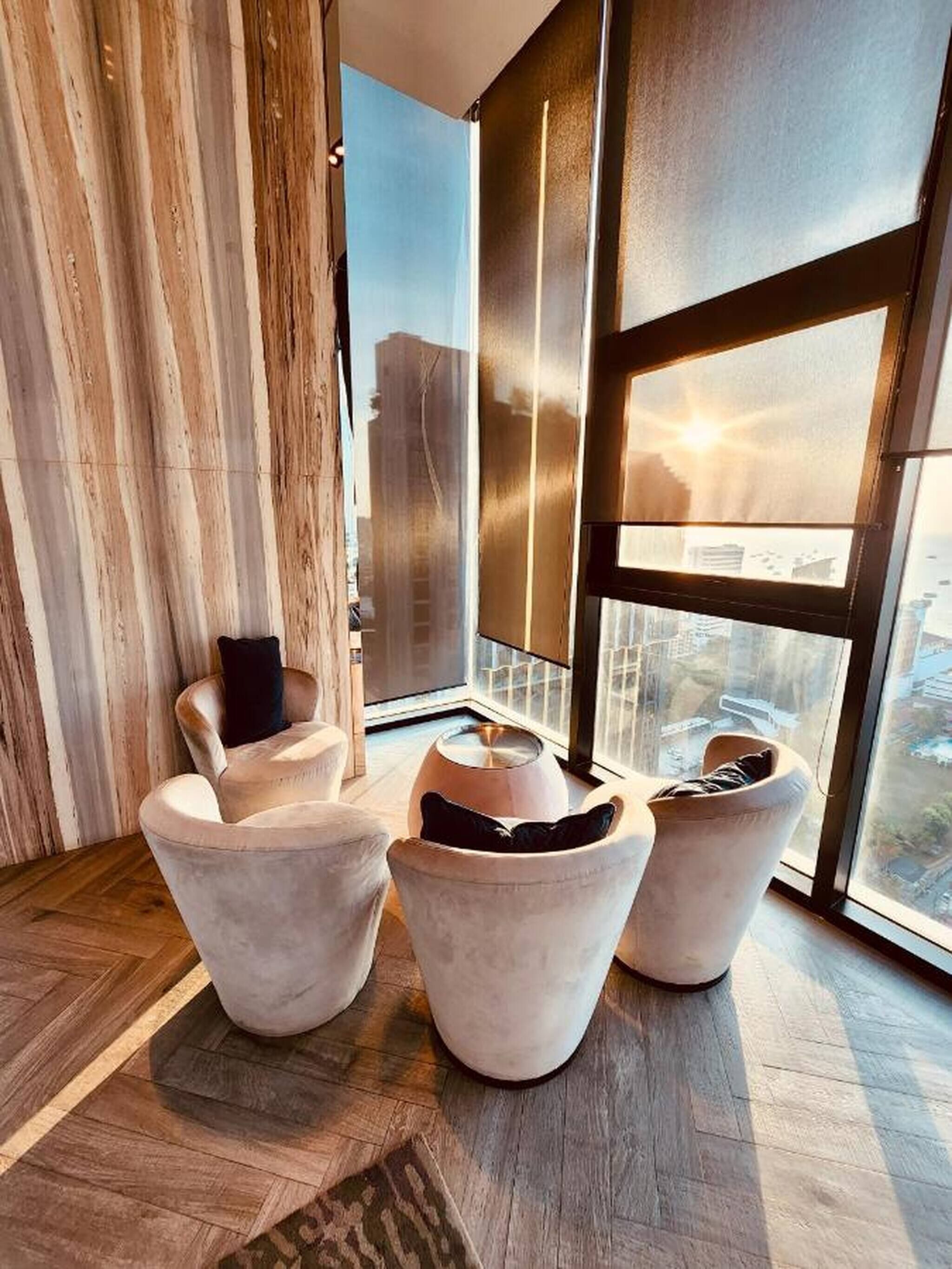 A modern living room with a large window, wooden flooring, and a city view.