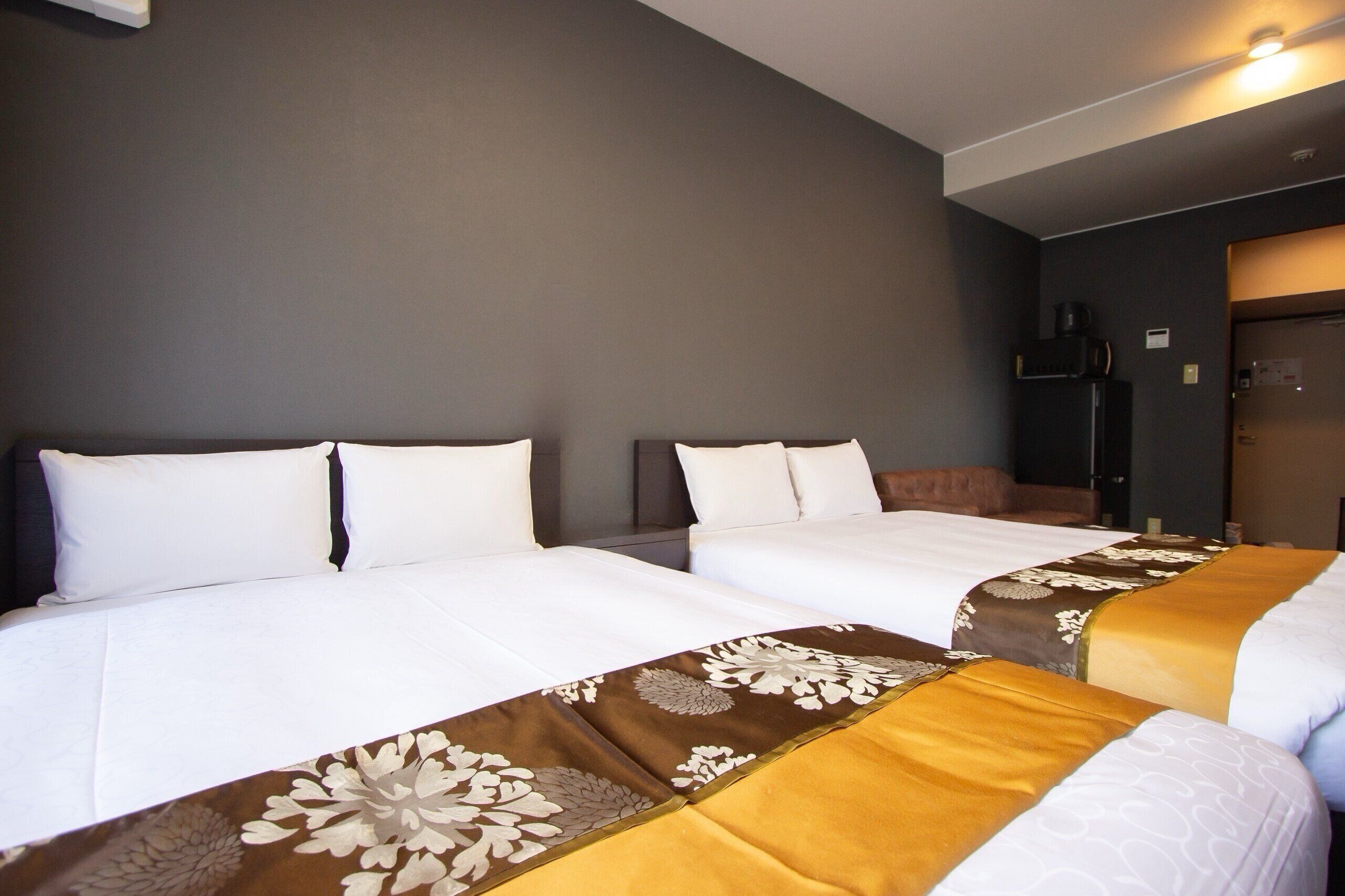 Een hotelkamer met twee bedden, elk voorzien van witte lakens en decoratieve hoofdeinden.