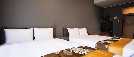 Quarto de hotel com duas camas, cada uma com roupa de cama branca e cabeceiras decorativas.