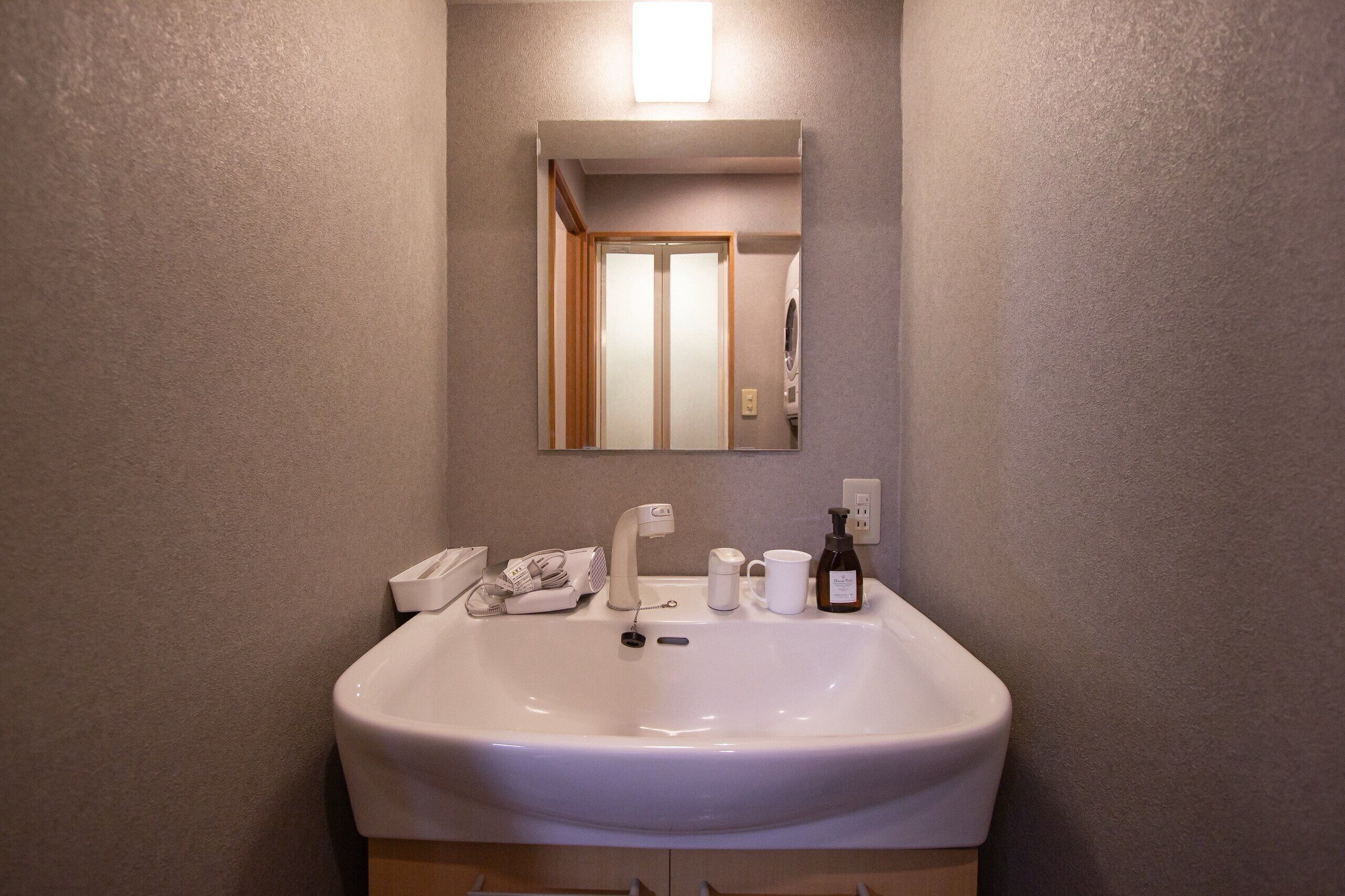 Un baño con un lavabo blanco, un espejo y un perchero para toallas.