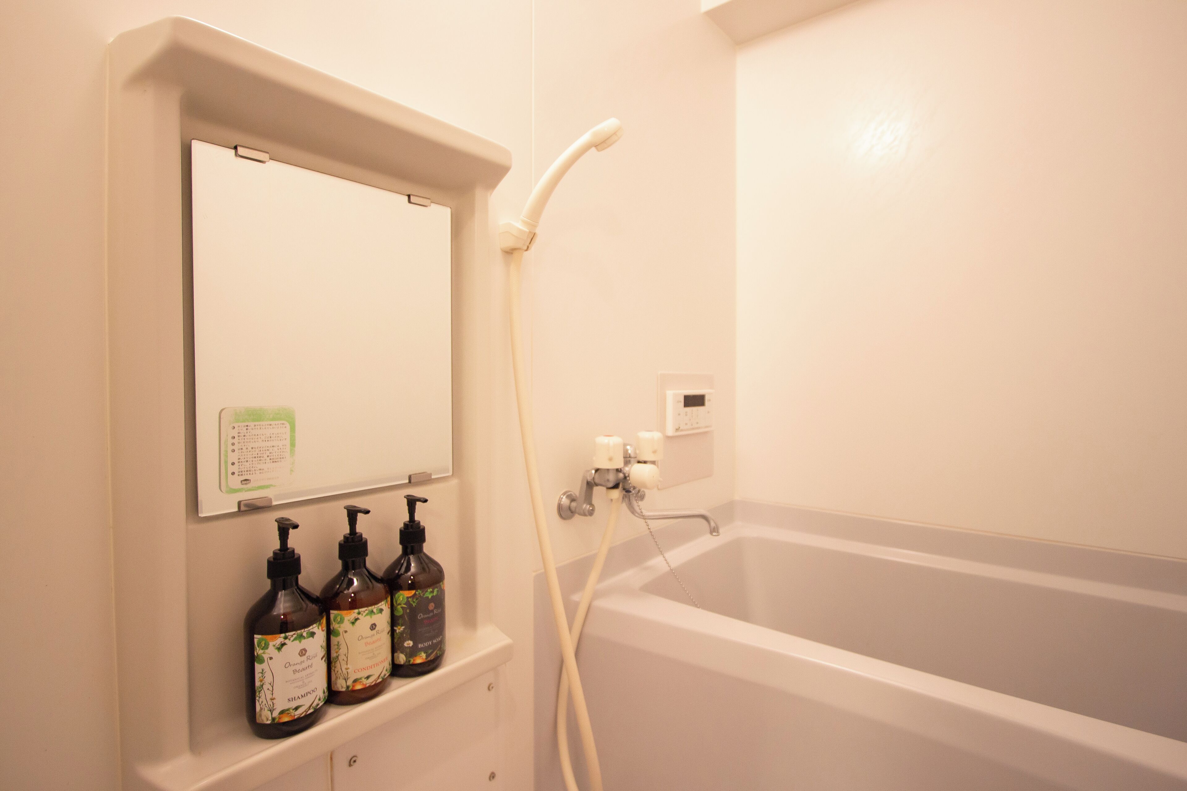 A bathroom with a bathtub, a mirror, and three bottles of shampoo.