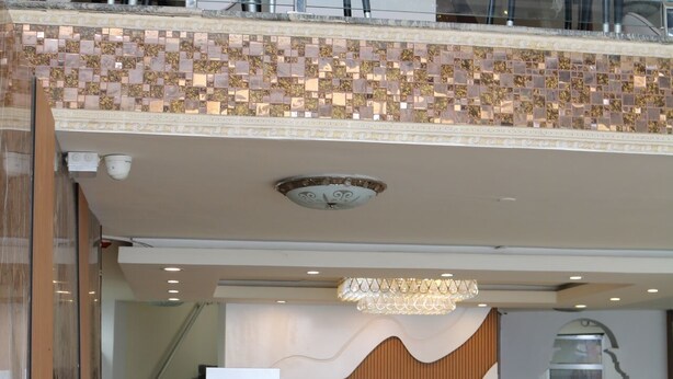 A hotel lobby with a reception desk, seating area, and a staircase leading to an upper level.