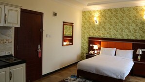 A hotel room with a bed, nightstands, a mirror, and a wardrobe.