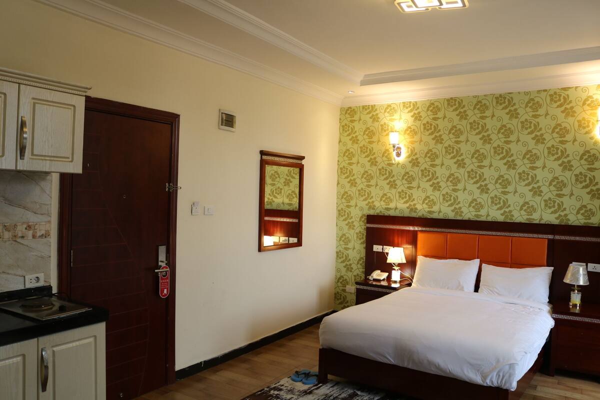 A hotel room with a bed, nightstands, a mirror, and a wardrobe.