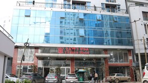 The exterior of the Hilton Hotel with a modern glass facade and a sign indicating its name.