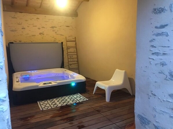 Ein kleiner Raum mit einer Badewanne, einem weißen Kunststoffstuhl und einer Leiter an der Wand.