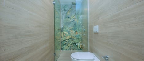 A narrow bathroom with a toilet, a glass shower enclosure, and a wall with a tropical mural.