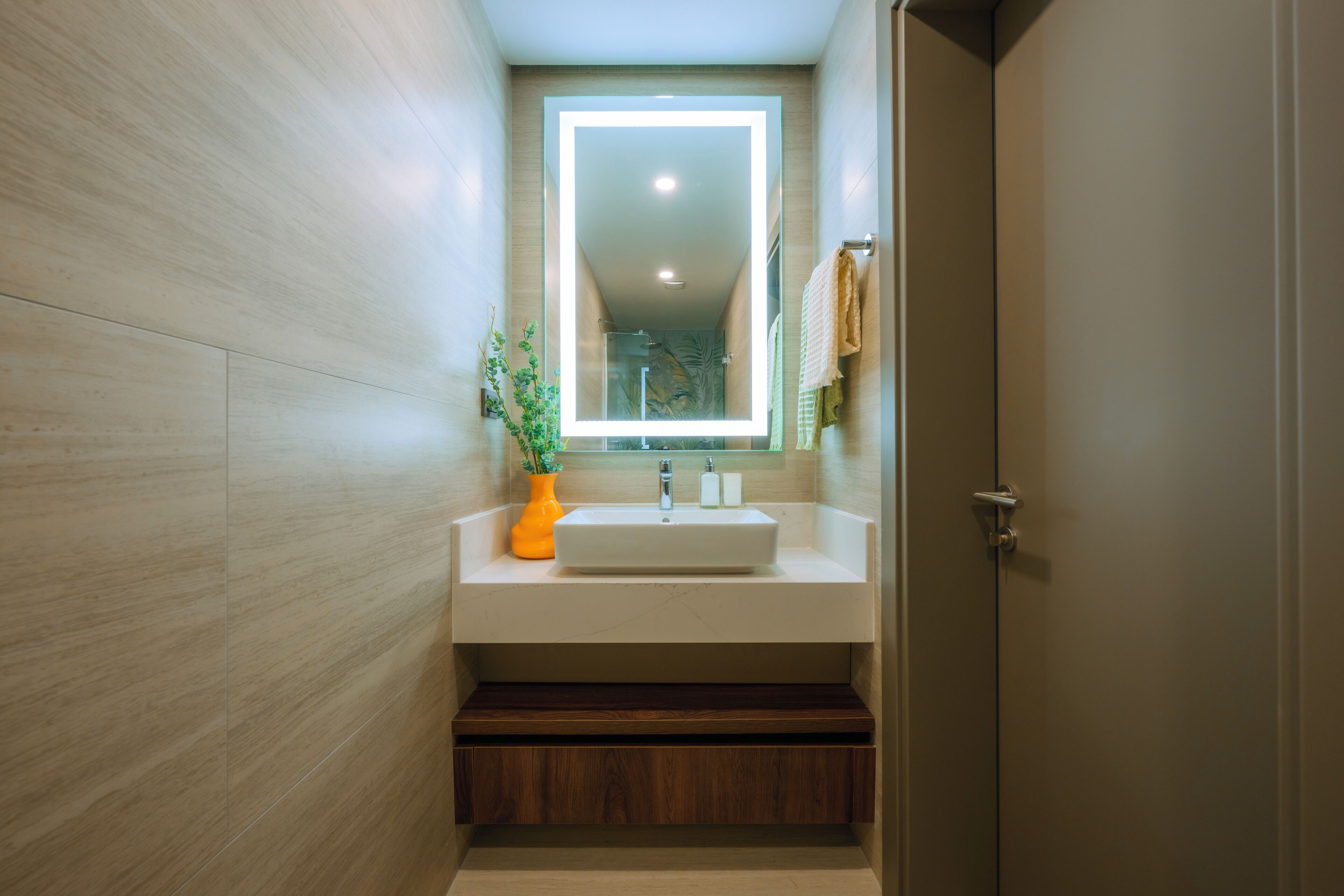 A modern bathroom with a white sink, a mirror, and a wooden cabinet.