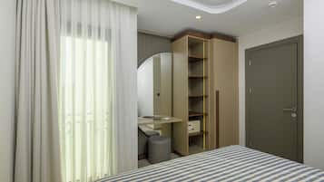 A hotel room with a bed, a desk, a mirror, a wardrobe, and a door.