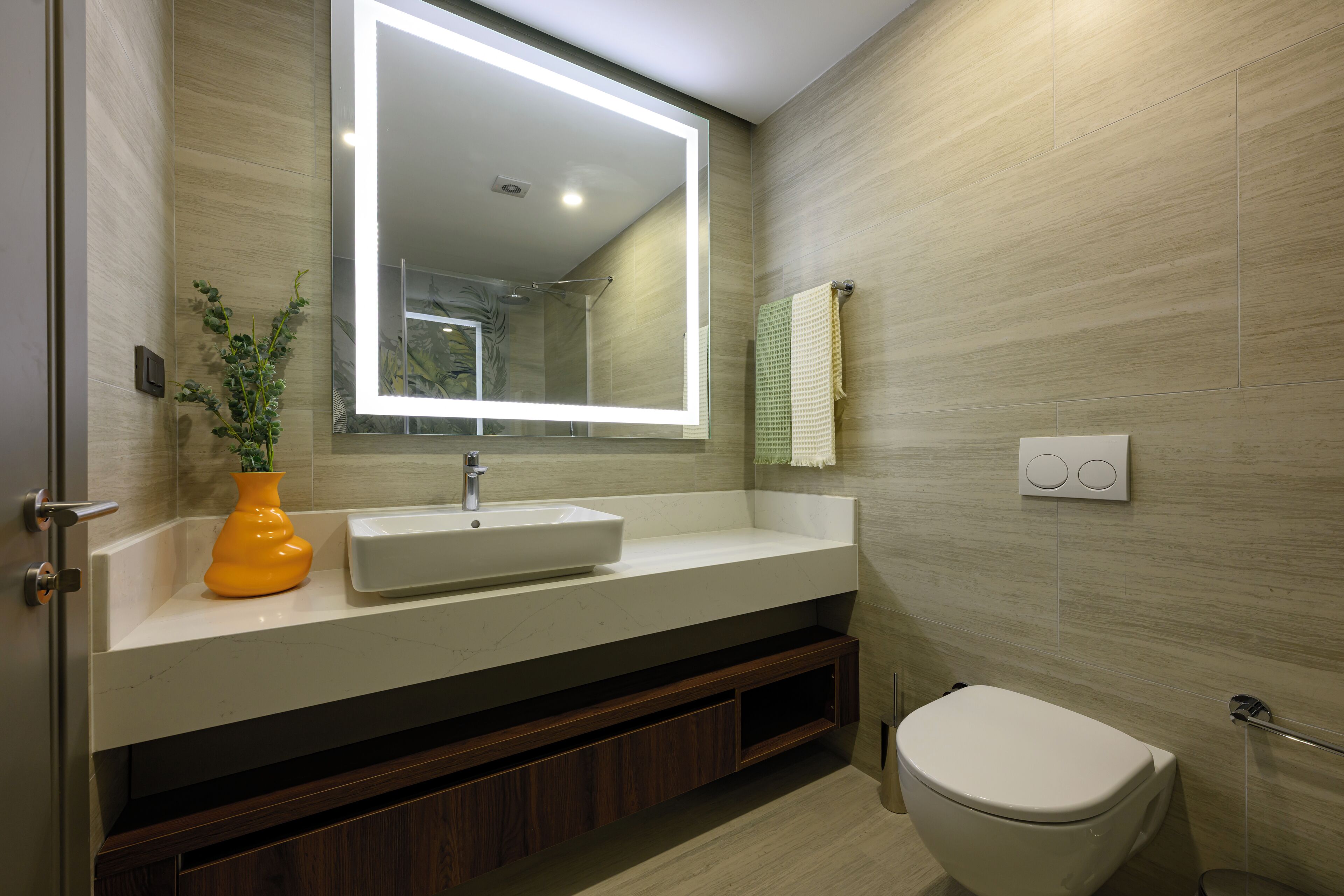 Une salle de bain moderne avec un grand miroir, un lavabo blanc et des toilettes.