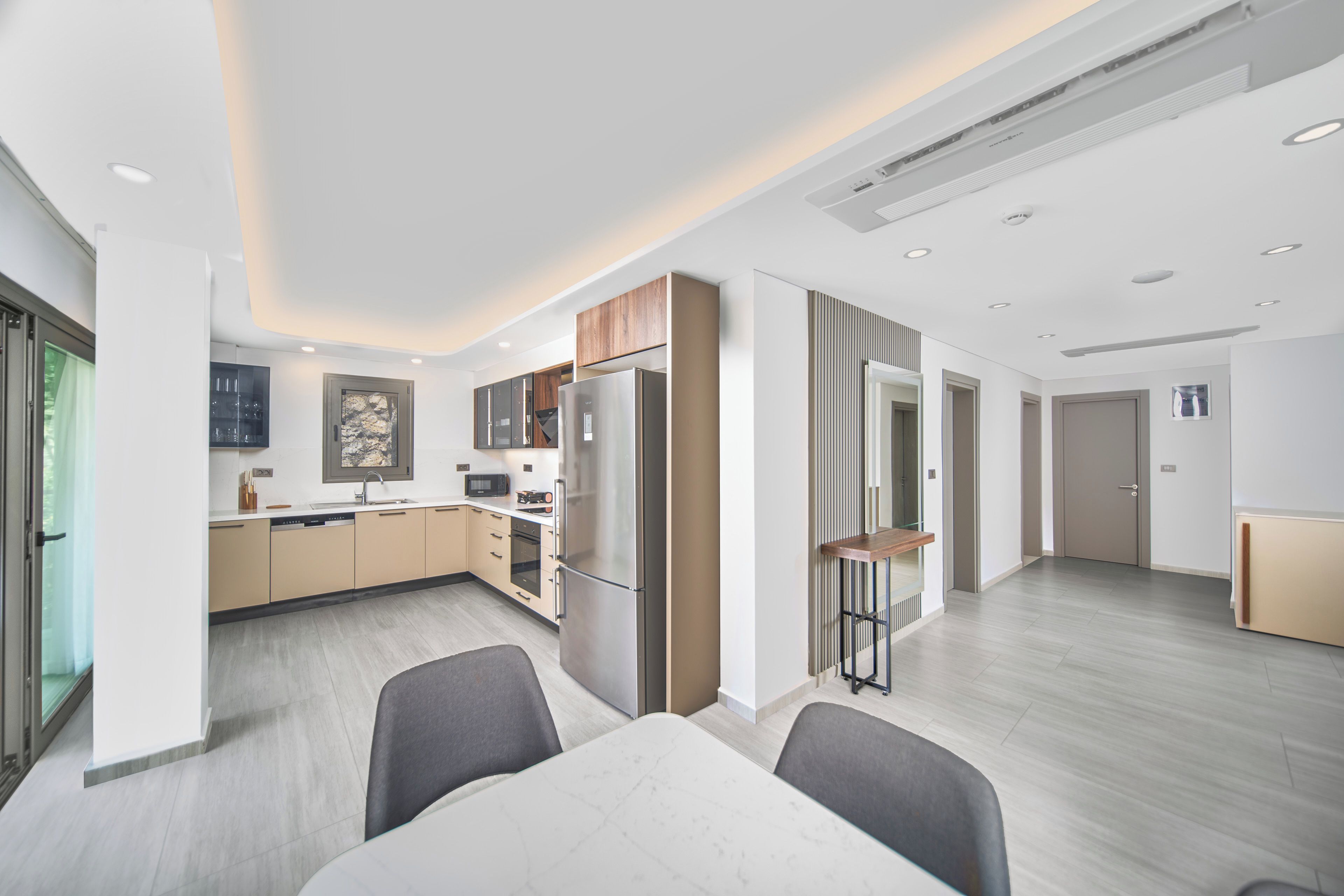 A modern kitchen with a built-in microwave, refrigerator, and oven. There is a dining area with a table and chairs.