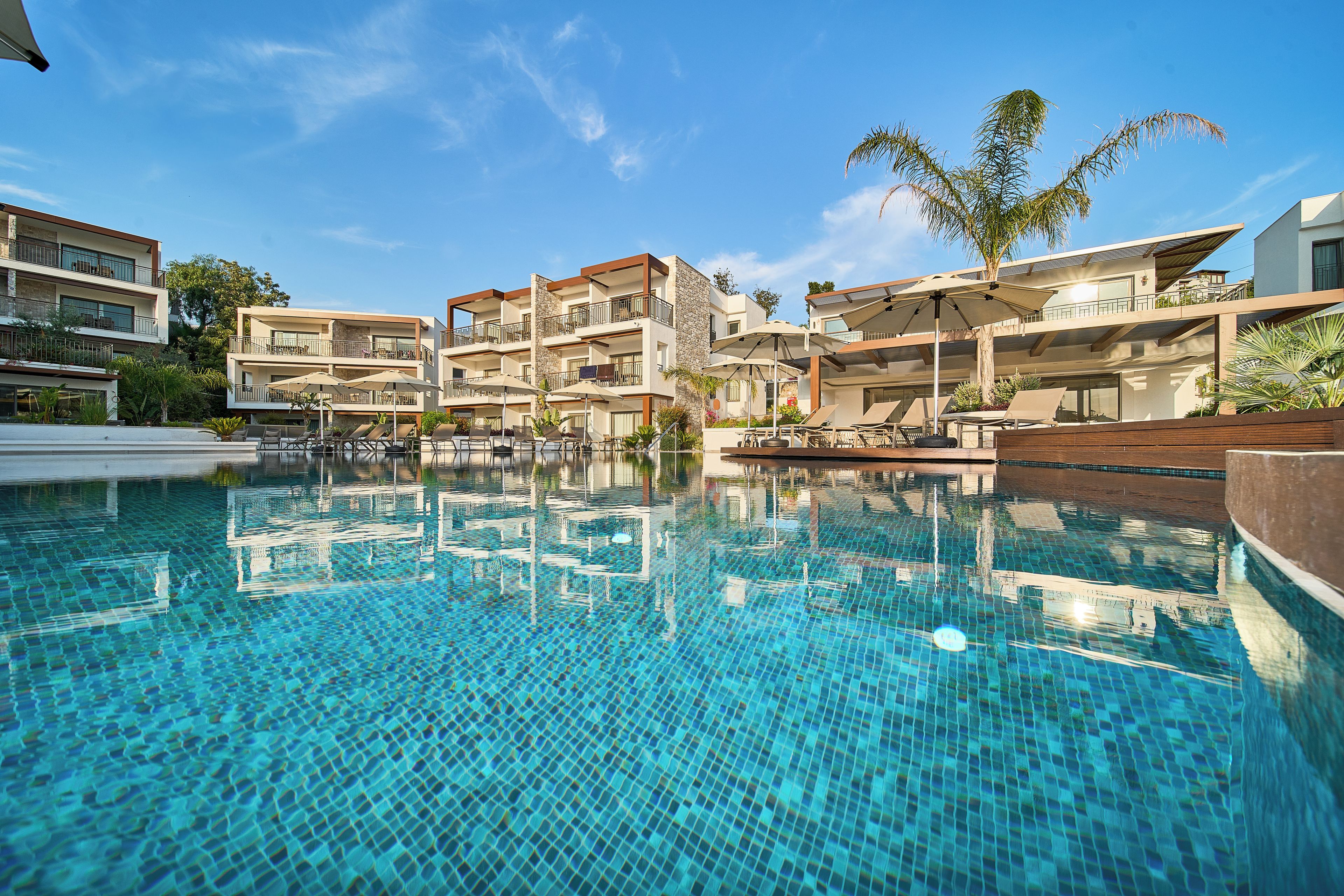 A hotel with a swimming pool, multiple balconies, and outdoor seating areas.