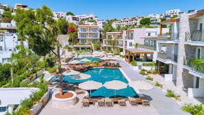 A resort with a central swimming pool, lounge chairs, and a stone wall. - Ayaz Suites (Bodrum)