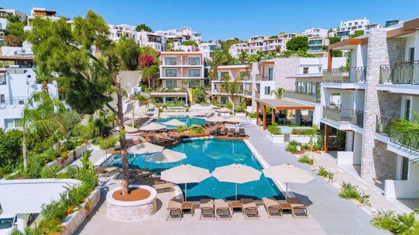 A resort with a central swimming pool, lounge chairs, and a stone wall. - Ayaz Suites (Bodrum)