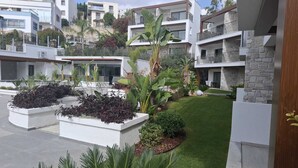 Un complexe résidentiel moderne composé de plusieurs immeubles à deux étages, agrémenté de jardins paysagers et d’une pelouse bien entretenue.