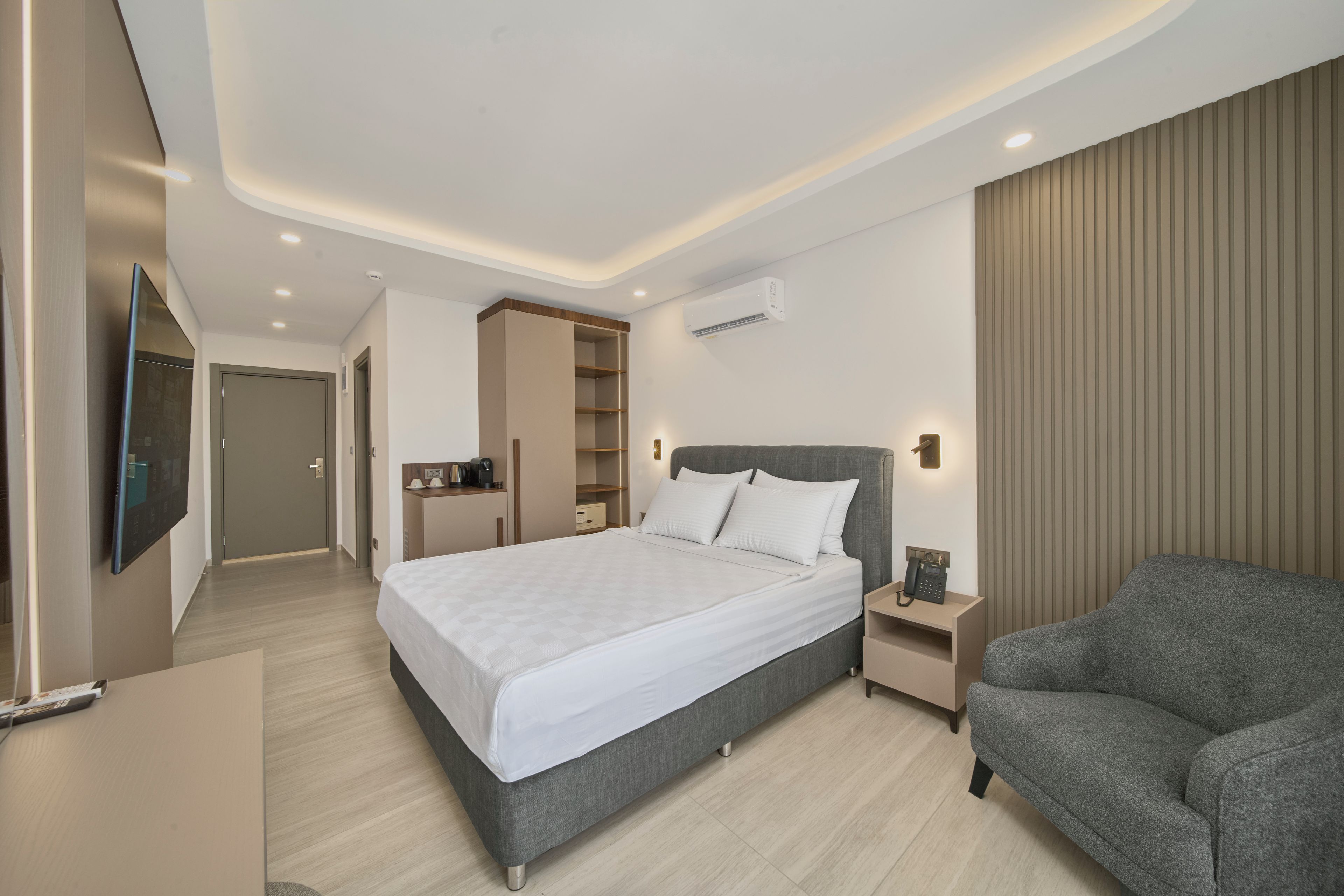 Une chambre d’hôtel moderne dotée d’un grand lit, de tables de chevet, d’un coin salon et d’une armoire intégrée.